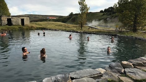 People relax in the waters of the Secret Lagoon geothermal spa.