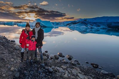 A family stand together in front of the Jokulsarlon glacier lagoon.