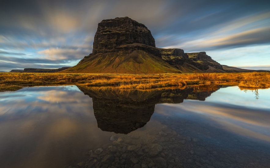 ภูเขา Lomagnupur ทางตอนใต้ของไอซ์แลนด์ในช่วงฤดูใบไม้ร่วงพร้อมเงาสะท้อนในน้ำเบื้องล่าง