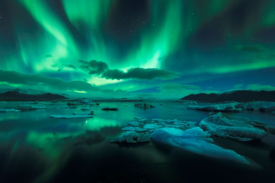 The Jokulsarlon Glacial Lagoon in late fall or early winter with northern lights or aurora borealis lighting up the water and the icebergs