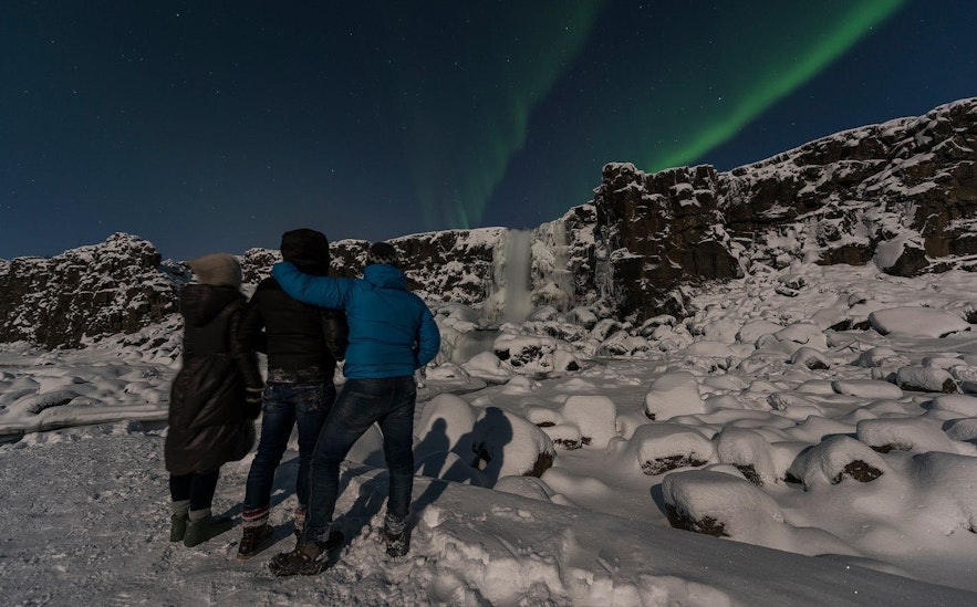 Group of travelers watching the northern lights in the sky at Thingvellir National Park