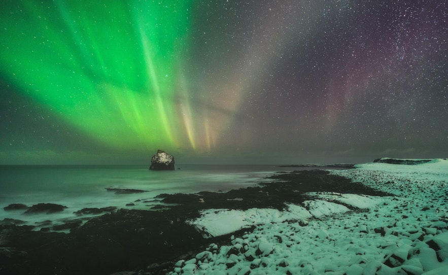 Northern lights over snowy and icy sea cliff on the Reykjanes Peninsula