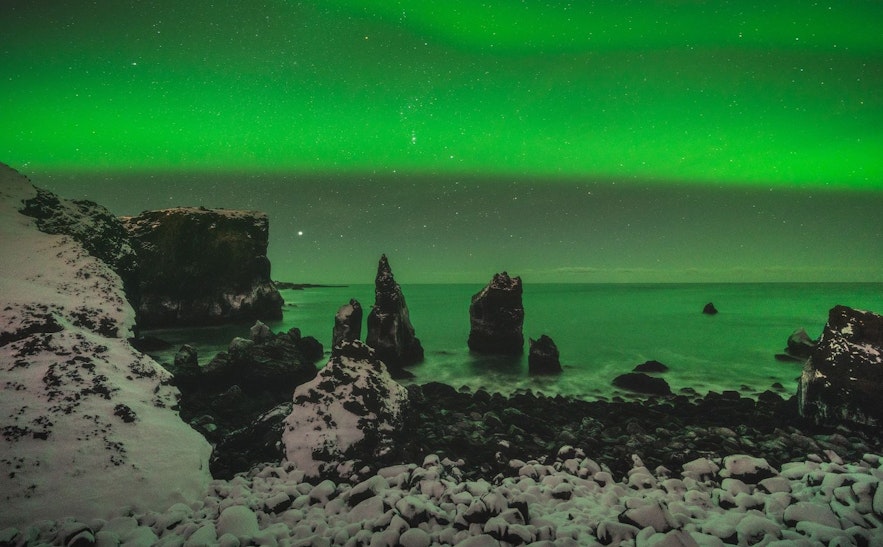 Northern lights over Valahnjukar on the Reykjanes peninsula in winter with the lights reflecting in the sea