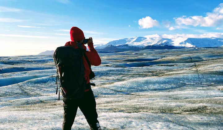A traveler standing on a glacier takes a photo of the ice cap.