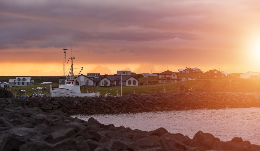 The cozy marina in Keflavik with a boat and a hotel in background during sunset